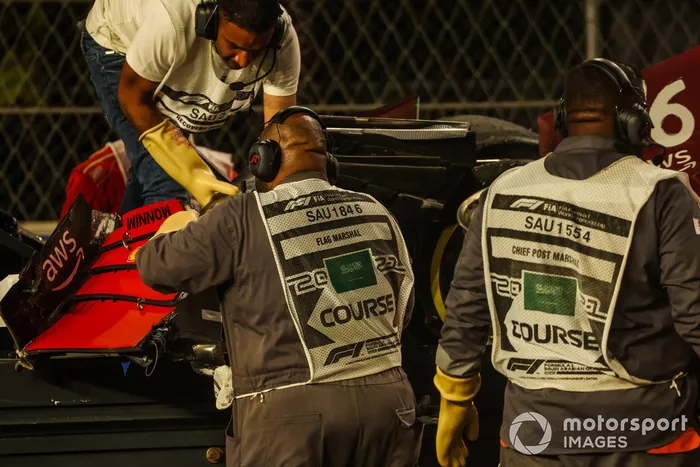Un oficial de pista retira el alerón delantero del coche de Charles Leclerc, Ferrari SF21, del circuito