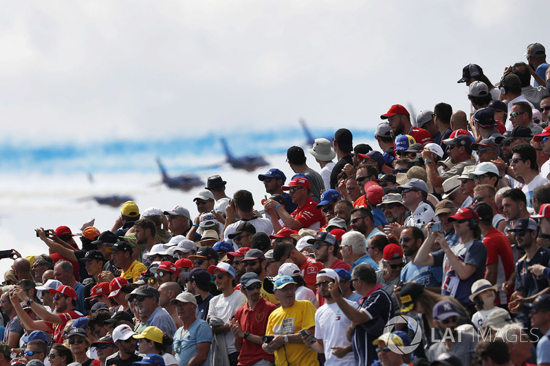 La multitud observa mientras el equipo de acrobacias aéreas de la Fuerza Aérea Francesa, La Patrouille de France, pasa volando en su Dassault Alpha Jet Es