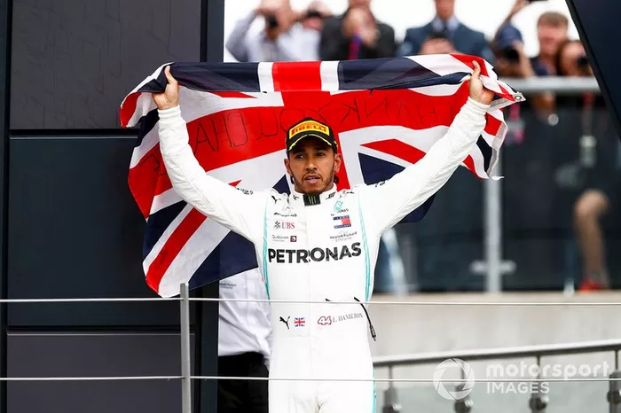 El ganador de la carrera Lewis Hamilton, Mercedes AMG F1 celebra en el podio con una bandera 