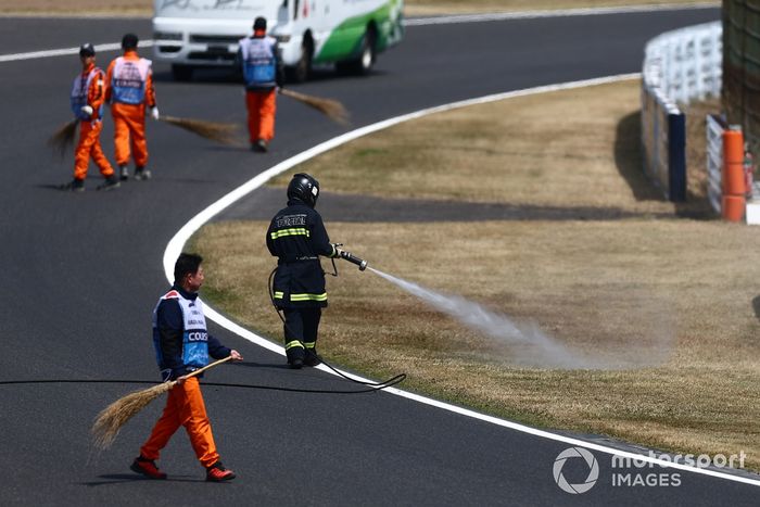 Un bombero rocía la hierba del lateral de la pista para humedecerla tras los incendios ocurridos durante los entrenamientos finales.