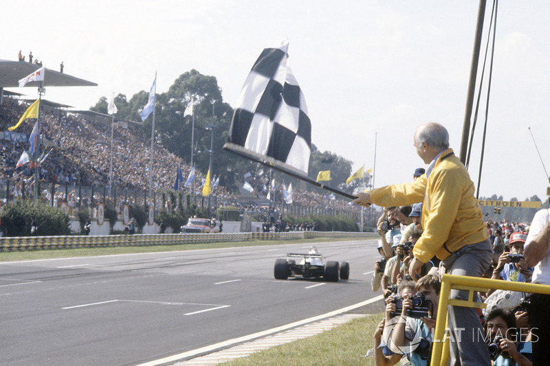 Juan Manuel Fangio brandit le drapeau à damier pour Carlos Reutemann, Williams FW07C-Ford Cosworth