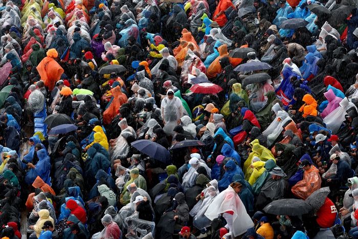 El público se protege de la lluvia en una grada.