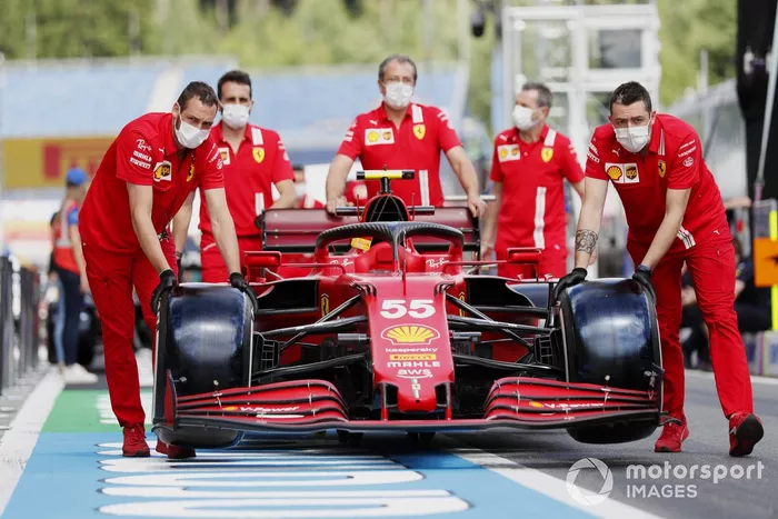 Los mecánicos de Ferrari empujan el coche de Carlos Sainz Jr., el Ferrari SF21, por el pitlane