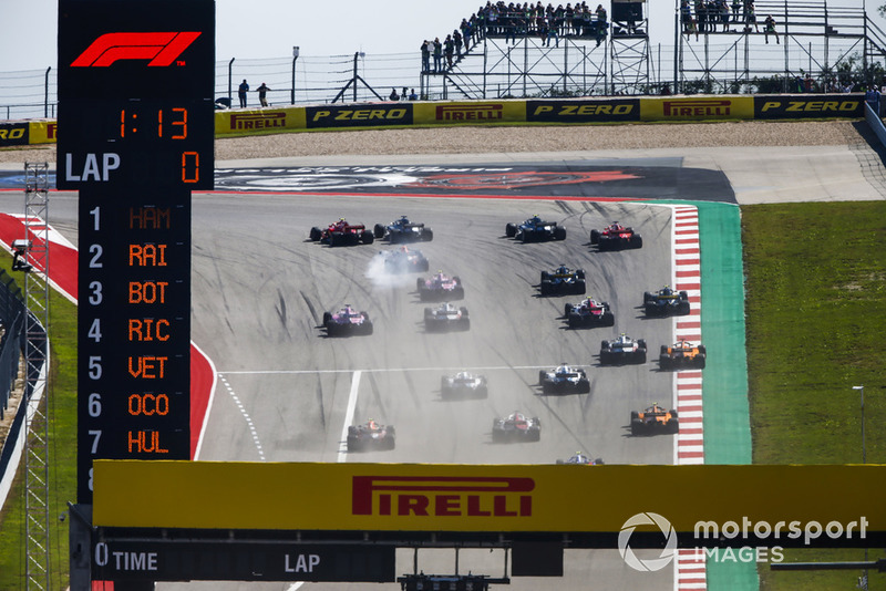 Kimi Raikkonen, Ferrari SF71H, passes Lewis Hamilton, Mercedes AMG F1 W09 EQ Power+, in the first turn as they lead the field at the start of the race