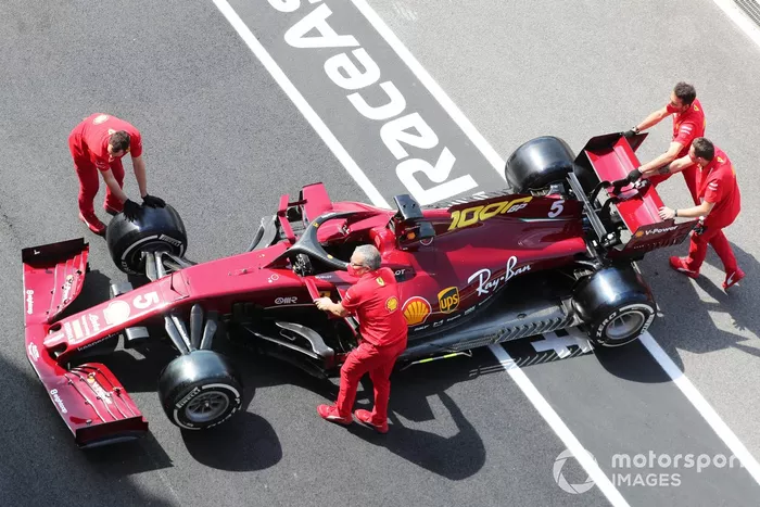 Membri del team Ferrari spingono la vettura di Sebastian Vettel Ferrari SF1000 in pit lane

