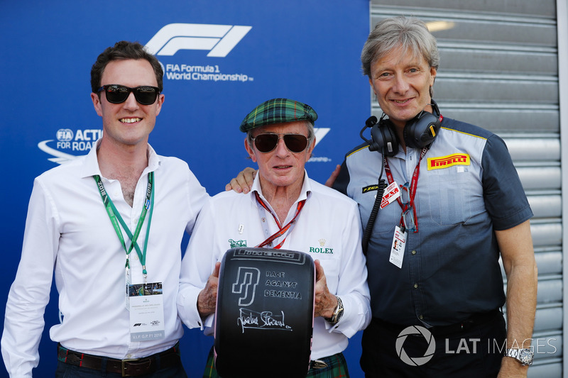 Sir Jackie Stewart holds a tyre branded with the message Race Against Dementia