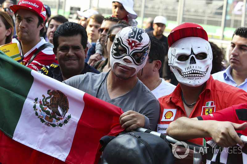 Fans in local attire attend the drivers' autograph signings in the pit lane