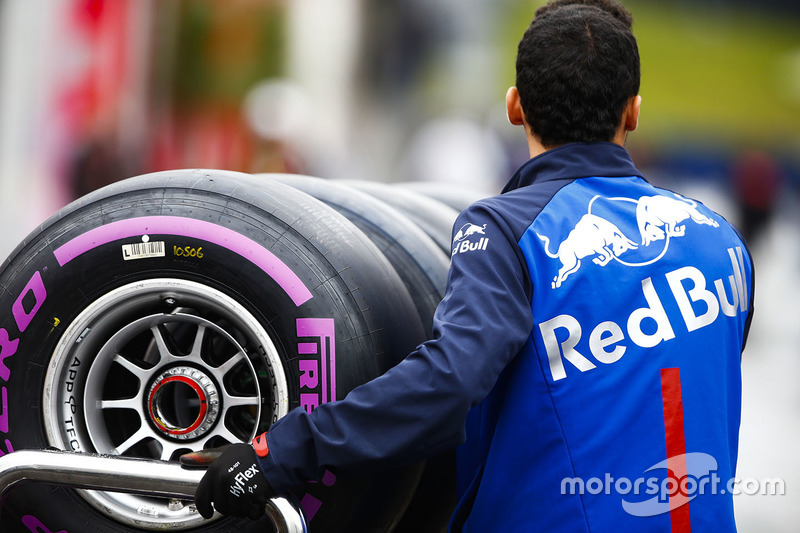 A Toro Rosso team member pushes a trolley of Pirelli tyres through the paddock