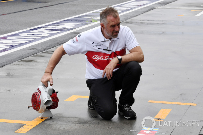 Les mécaniciens Sauber assèchent l'emplacement dans les stands