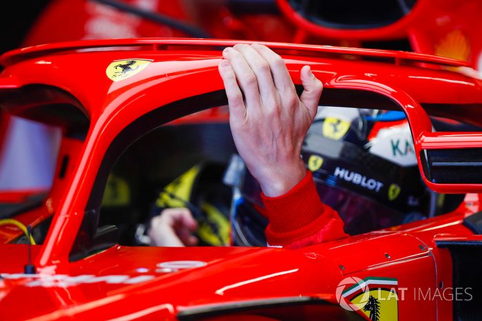 Kimi Raikkonen, Ferrari, rests a hand on his halo