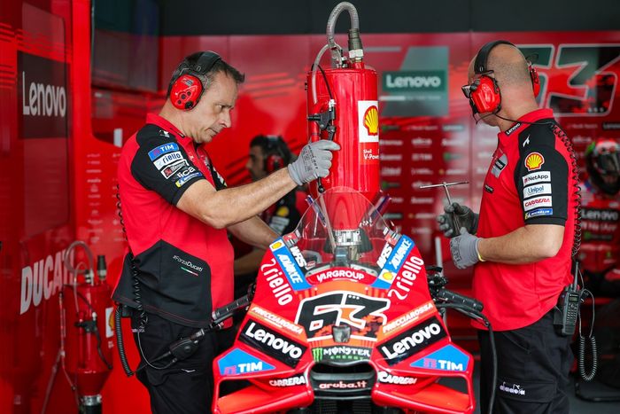 Два механика команды Ducati заправляют мотоцикл