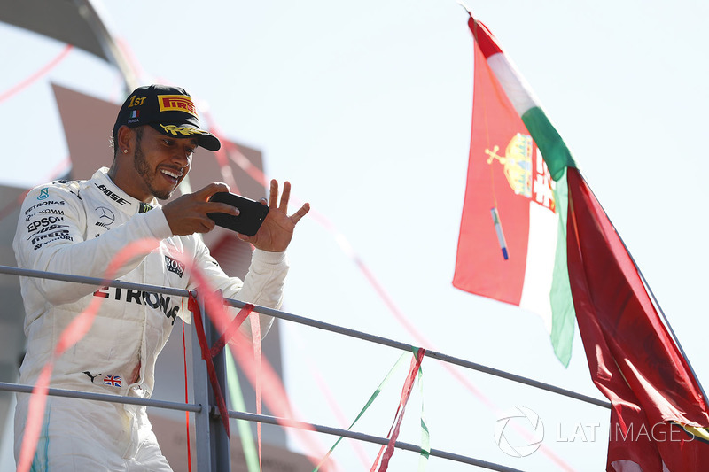 Race winner Lewis Hamilton, Mercedes AMG F1, takes a photo from the podium