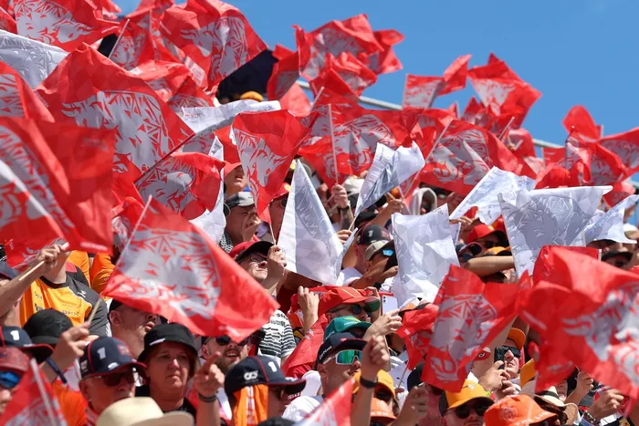 Fans wave red and white flags in the grandstand .