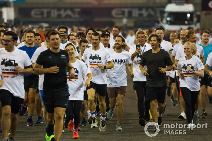 Sebastian Vettel, Aston Martin, es acompañado en una carrera alrededor del circuito por los miembros del equipo con la playera de Danke Seb como parte de su despedida en su último Gran Premio