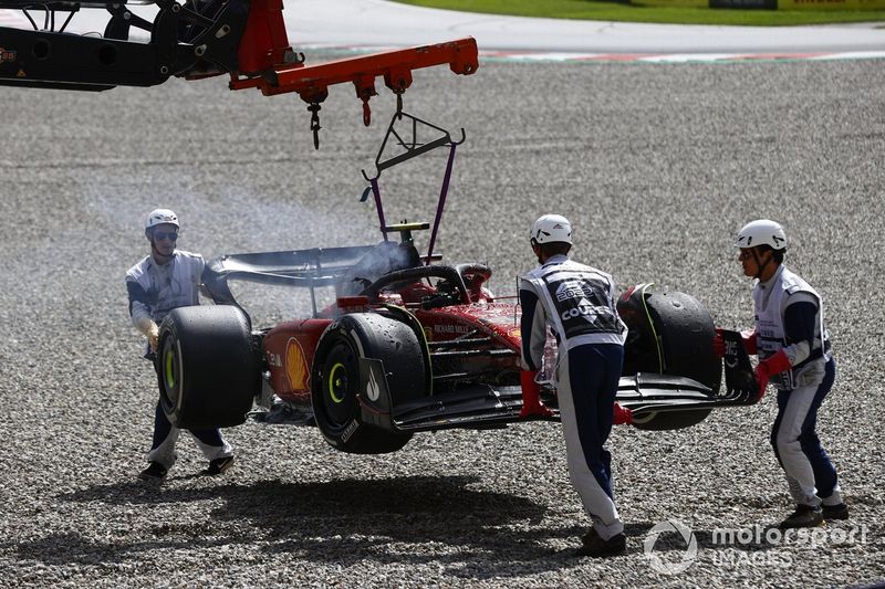 Los oficiales de pista retiran del circuito el coche incendiado de Carlos Sainz, el Ferrari F1-75