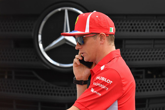 Kimi Raikkonen, Ferrari, al telefono davanti al logo Mercedes