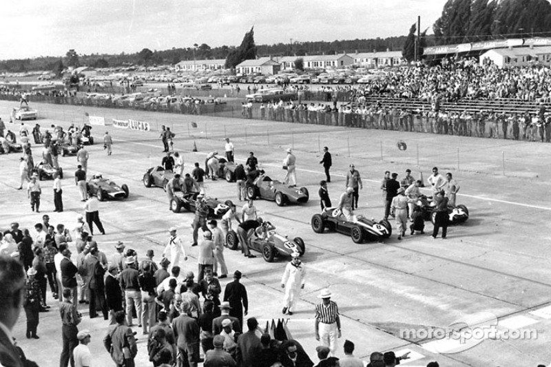 Jack Brabham (car no.8) climbs into his Cooper-Climax on the front row of the grid