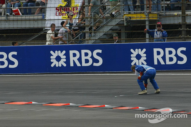 A marshall goes to recover bottles and cans of beer thrown on the track