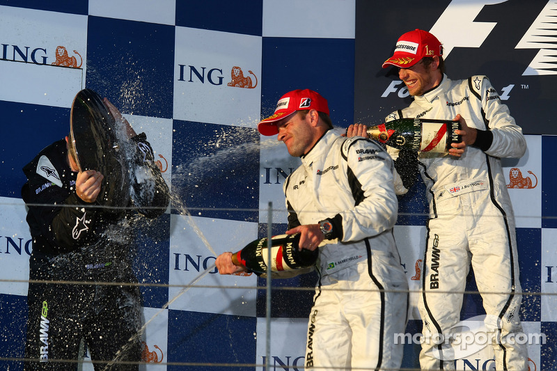 Podium : Ross Brawn utilise son trophée pour rester sec face à Rubens Barrichello et Jenson Button